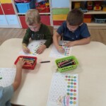 Dzieci przy stoliku uzupełniają kartę pracy.