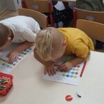 Dzieci przy stoliku uzupełniają kartę pracy.
