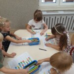 Dzieci przy stoliku uzupełniają kartę pracy.