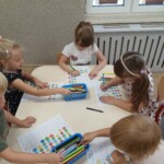 Dzieci przy stoliku uzupełniają kartę pracy.