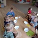 Dzieci siedzą przy stole z miseczkami