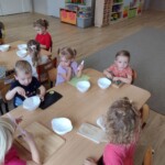 Dzieci siedzą przy stole z miseczkami