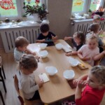 Dzieci siedzą przy stole z miseczkami