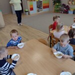 Dzieci siedzą przy stole z miseczkami